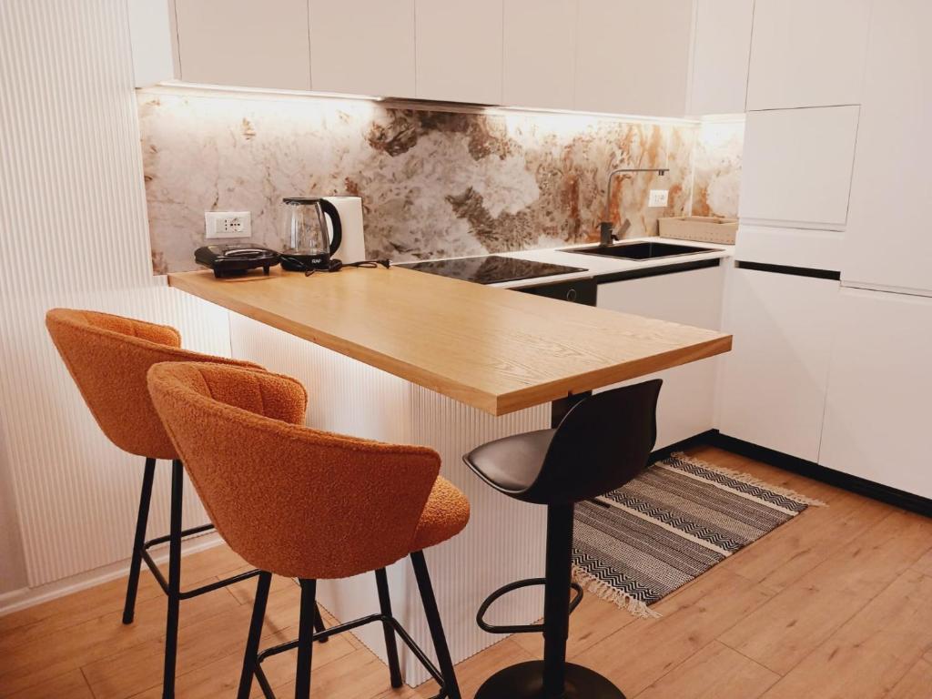 una cucina con un bancone in legno con tre sedie di Genci's Apartaments a Vlorë