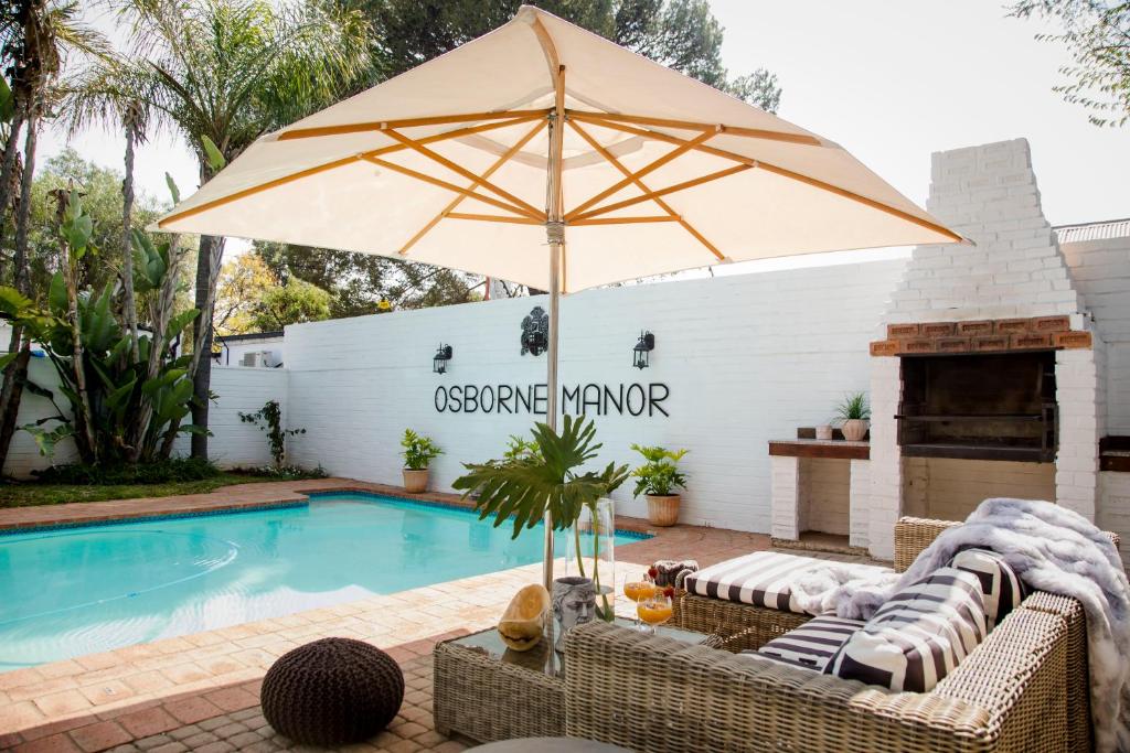 an umbrella and chairs next to a swimming pool at Osborne Manor Luxury Guesthouse in Kimberley