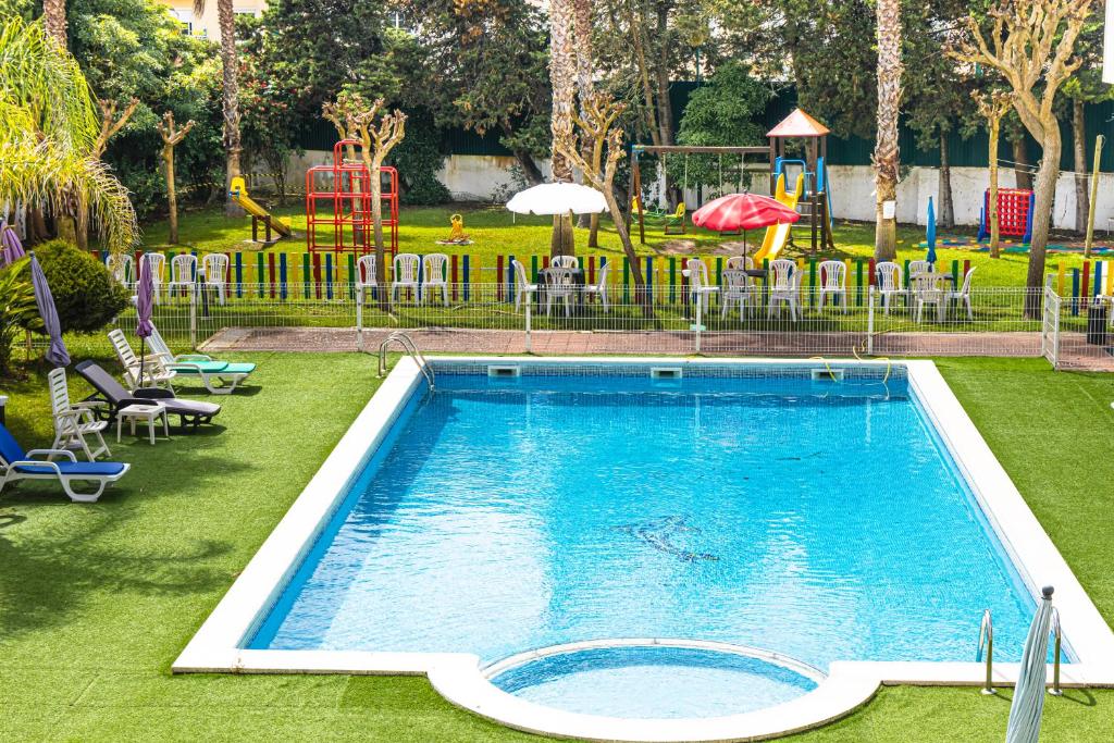 a swimming pool in a park with a playground at Hotel Caldas Internacional in Caldas da Rainha