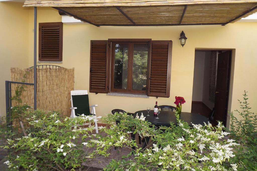 a patio of a house with a table and some flowers at Yellon House in Santa Maria Navarrese
