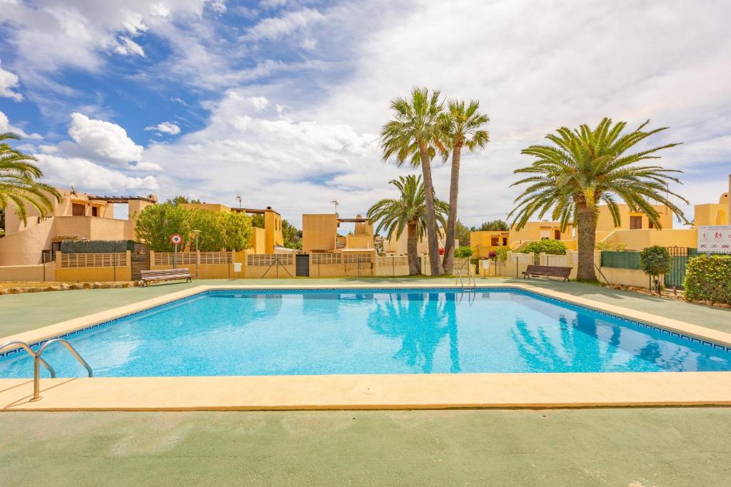 Una gran piscina con palmeras y edificios. en Bungalow Salud - PlusHolidays, en Calpe