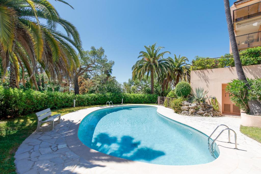 une piscine dans une cour avec des palmiers dans l'établissement Les terrasses de victoria, au Cannet