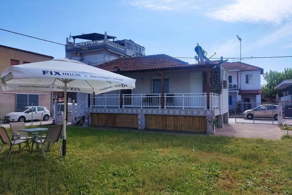 a house with a table and an umbrella in the yard at Nikis House in Keramoti