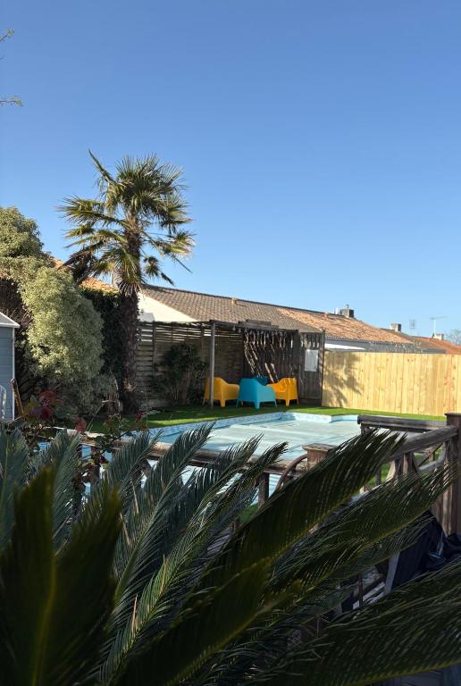 une piscine avec un palmier et un bâtiment dans l'établissement L’étoile de mer , maison en plein centre ville, à Bretignolles-sur-Mer
