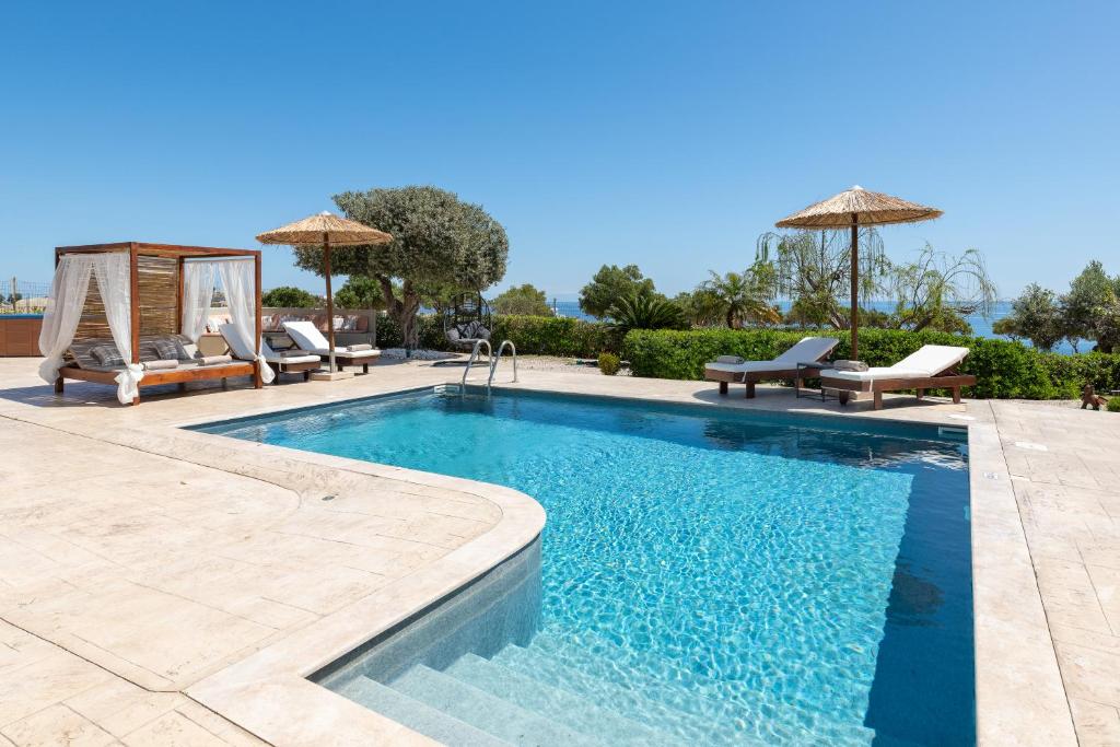 a swimming pool with chairs and umbrellas in a yard at Villa Alia in Archangelos