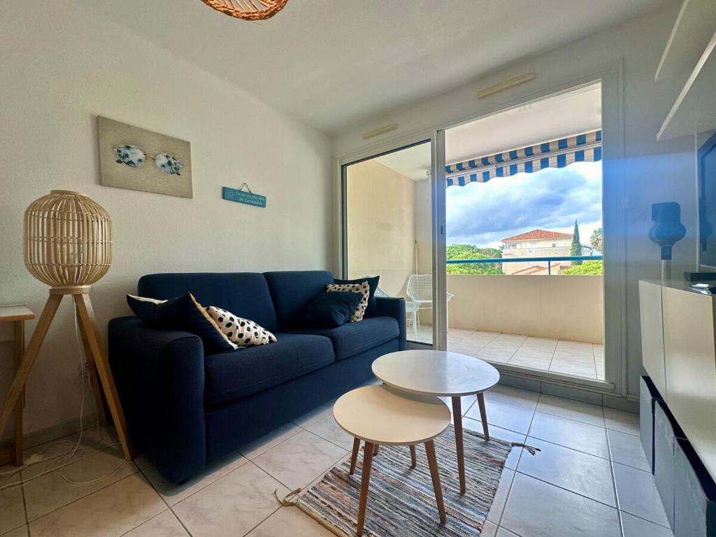 un salon avec un canapé bleu et une table dans l'établissement Cozy T2 avec piscine Le Lavandou, au Lavandou