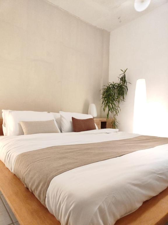 a large white bed in a bedroom with a plant at Fika Siargao - Cozy Island Home in General Luna in General Luna