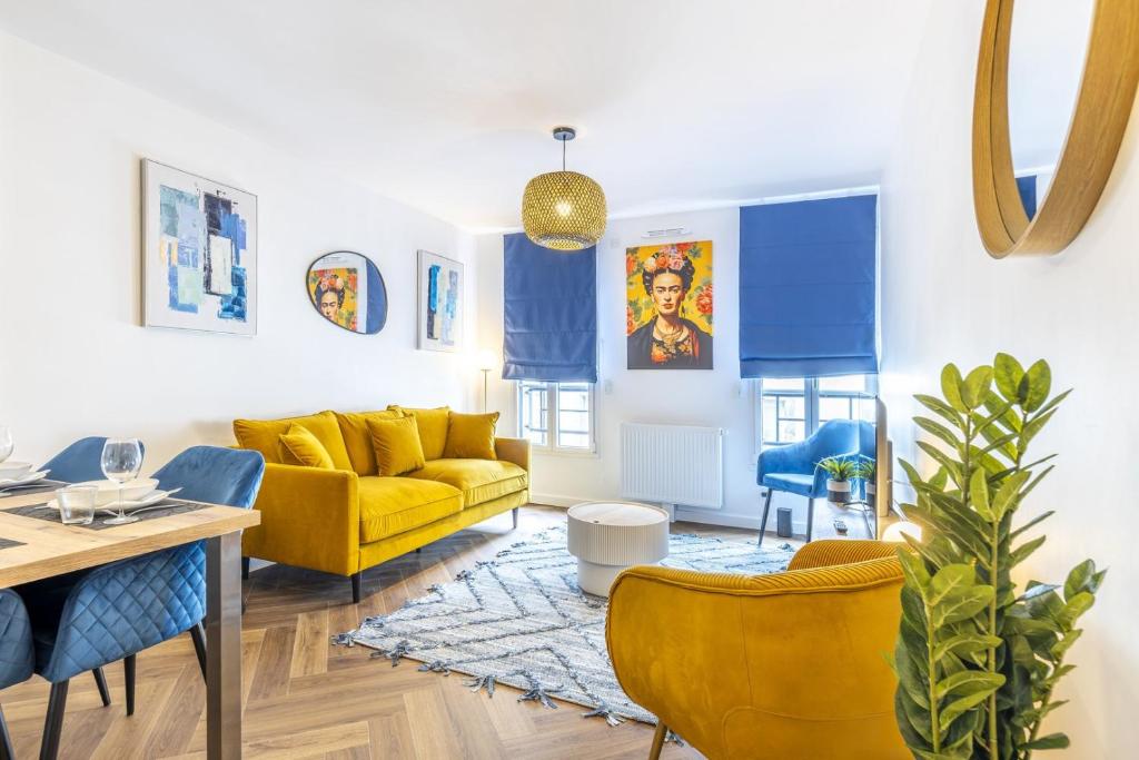 - un salon avec un canapé jaune et des fauteuils bleus dans l'établissement OIQIA • Armoria, à Quimper