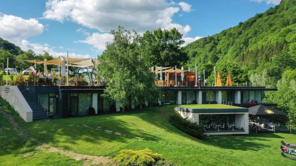 a building with a grassy yard next to a mountain at Pensiunea Atra Doftana in Teşila