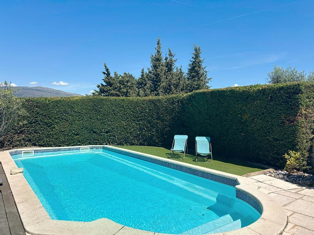 - une piscine avec 2 chaises à côté d'une haie dans l'établissement Rives d'Azur, à Mouans-Sartoux