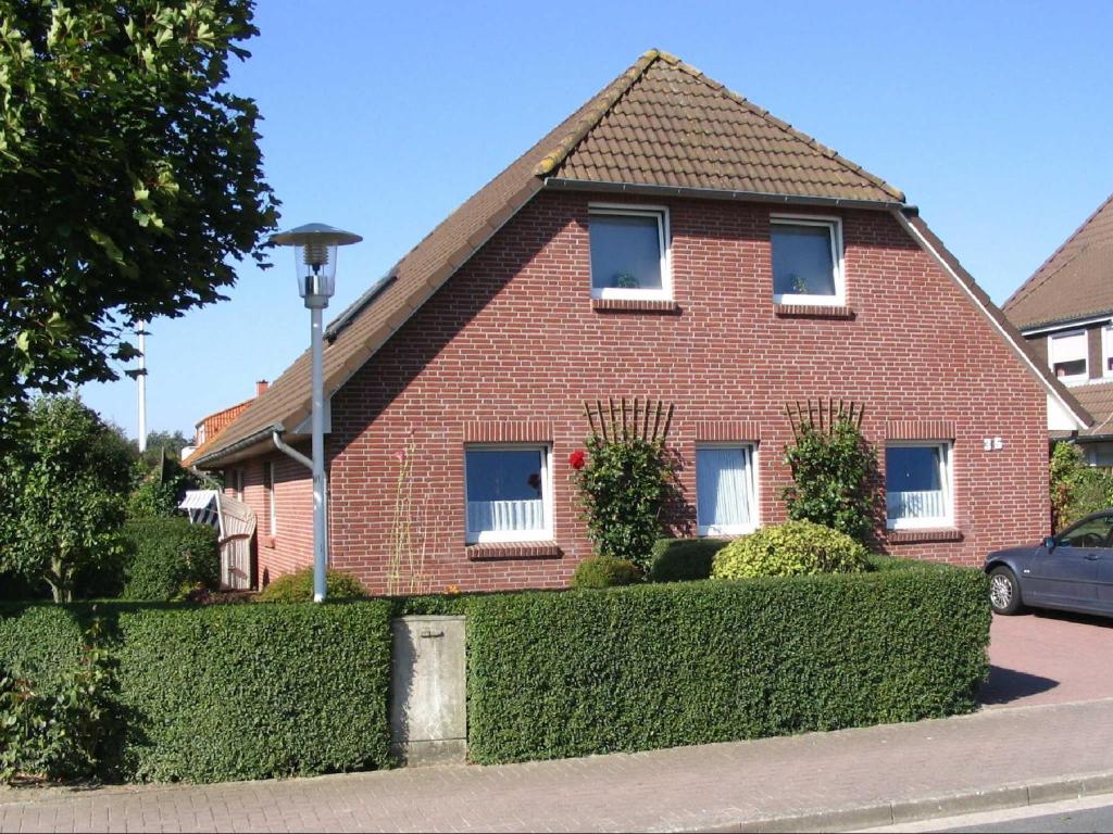 a red brick house with a hedge in front of it at Haus Leißner in Büsum