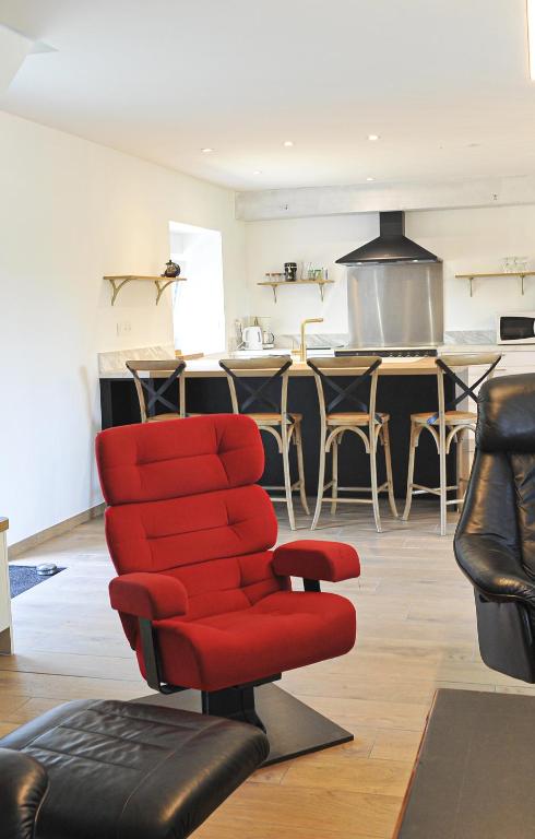 un fauteuil rouge dans un salon avec une cuisine dans l'établissement Maison de campagne en centre Finistère, à Lennon
