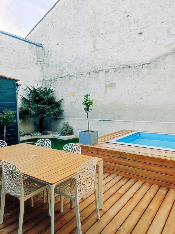 une terrasse en bois avec une table et des chaises ainsi qu'une piscine dans l'établissement Maison de ville au calme, à Cognac
