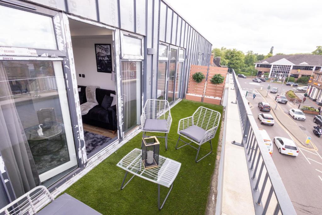 Un balcón de un edificio con sillas y una calle en Brand-New Top-Floor Flat with Stunning Balcony & Parking, en Borehamwood