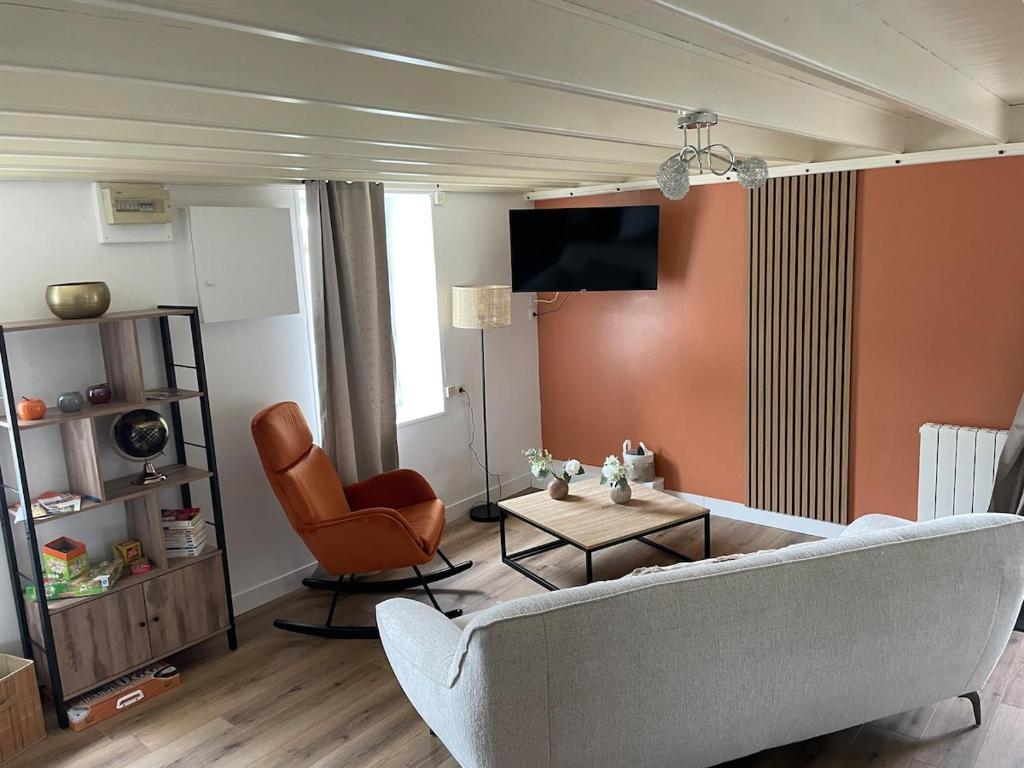 un salon avec un canapé et une chaise dans l'établissement Le Nid Familial, Maison cosy entre terre et mer, à Saint-Germain-de-Tournebut
