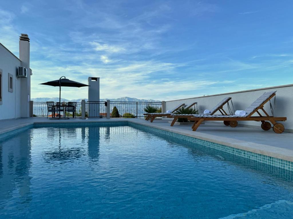 a swimming pool with benches and a table on a building at Apartman Domnius in Škrip