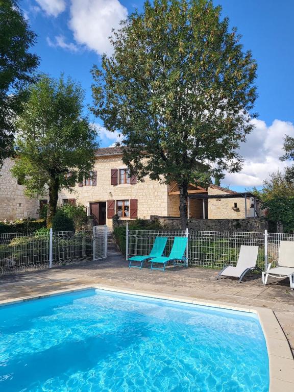 une piscine avec deux chaises et une maison dans l'établissement Mas Haut, à Loubers