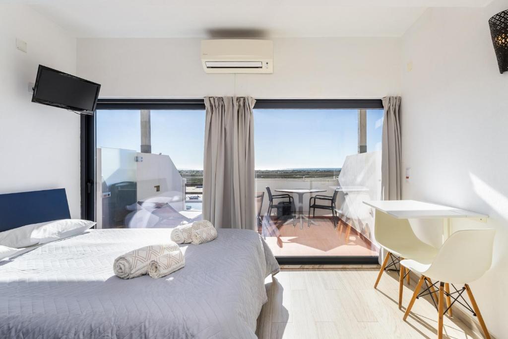 a bedroom with a bed and a large window at Cabanas de Tavira - Studio in Cabanas de Tavira