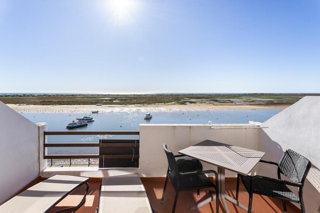 a balcony with a table and chairs and a view of the ocean at Cabanas de Tavira - Studio in Cabanas de Tavira