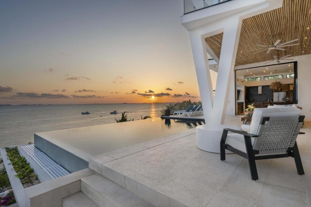a villa with a patio with a chair and the ocean at Spectacular New Oceanfront Villa Isla Mujeres in Isla Mujeres