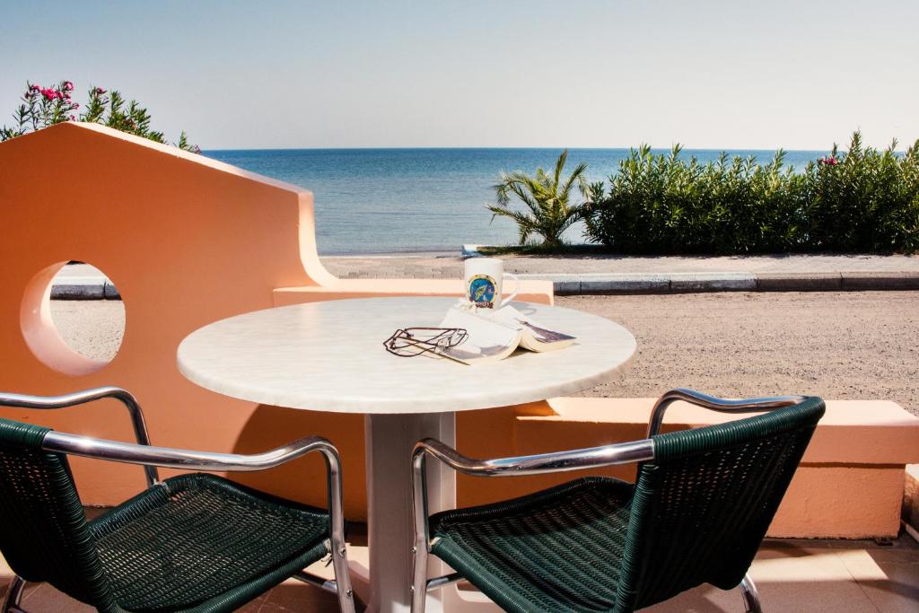 a table and chairs with the beach in the background at Limanaki Apartments in Faliraki