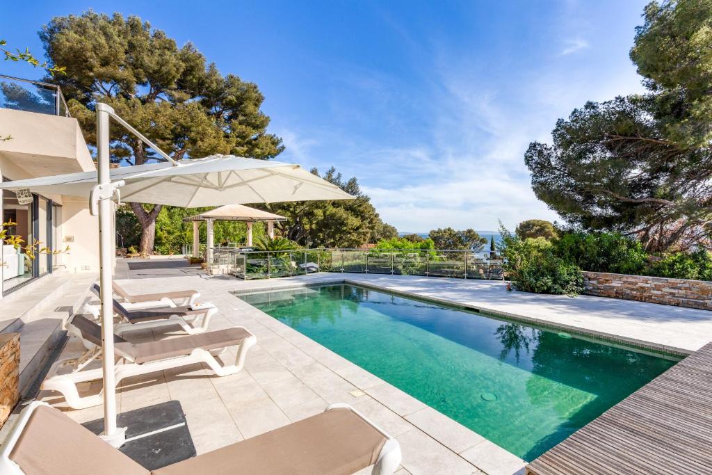 une piscine avec des chaises et un parasol à côté d'une maison dans l'établissement Demeure Domaine du Soleil, au Lavandou
