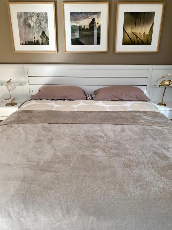 - un grand lit dans une chambre avec des photos sur le mur dans l'établissement Chambre Viviane, à Néant-sur-Yvel