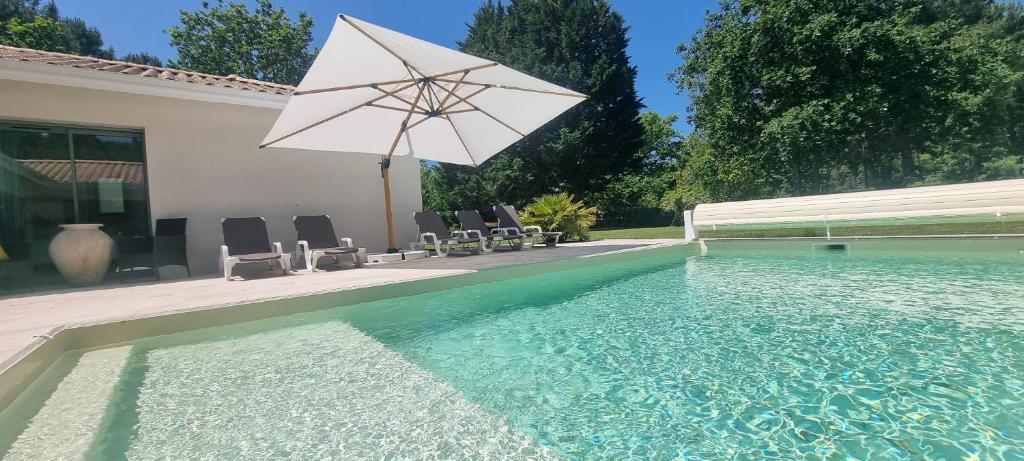 - une piscine avec un parasol et des chaises dans l'établissement Sunny Villa Nature, à Grayan-et-lʼHôpital