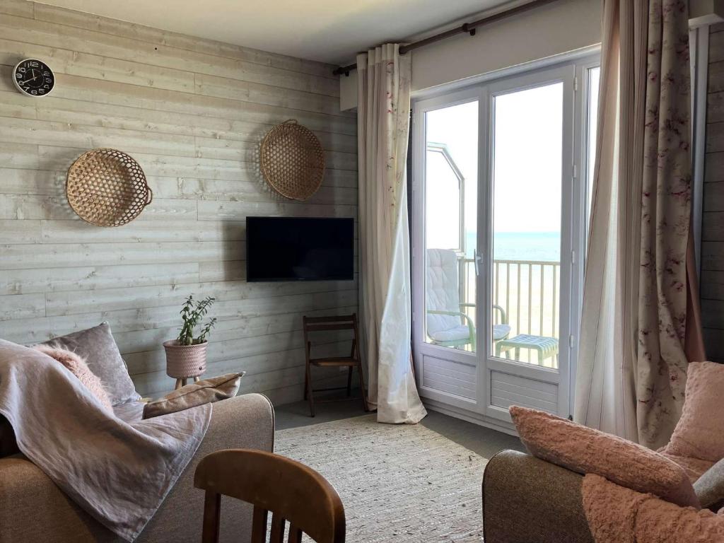 d'un salon avec une porte coulissante en verre s'ouvrant sur un balcon. dans l'établissement Violette - Saint Hilaire de Riez, à Saint-Hilaire-de-Riez