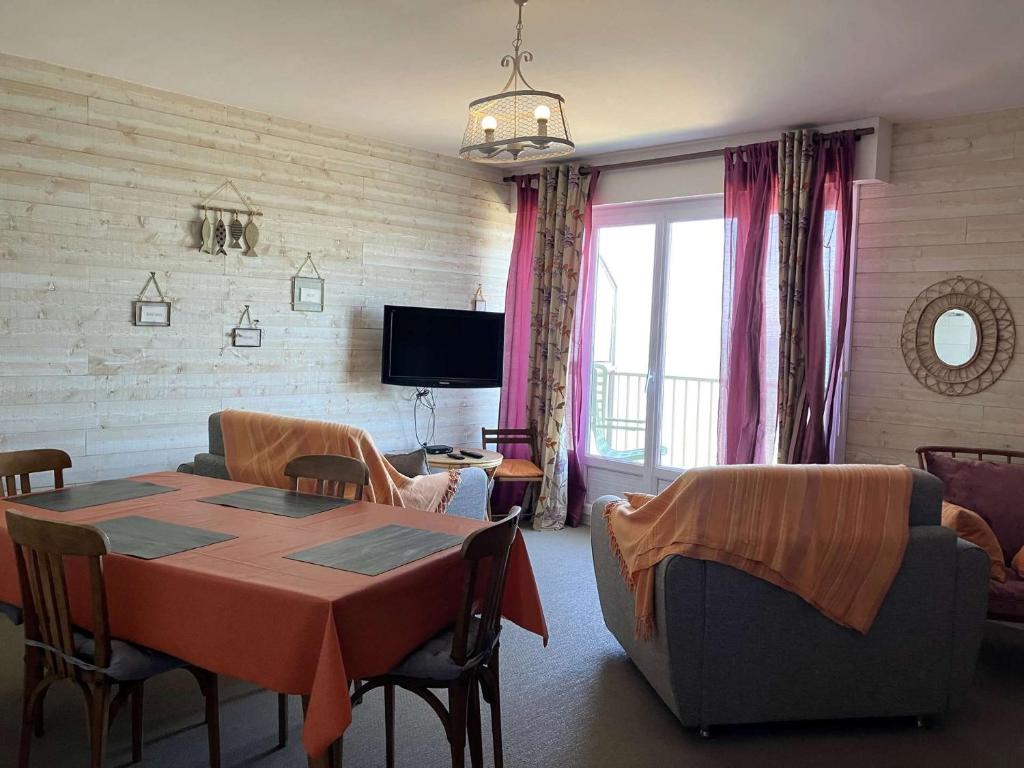 un salon avec une table, des chaises et une télévision dans l'établissement Passiflore - Saint Hilaire de Riez, à Saint-Hilaire-de-Riez