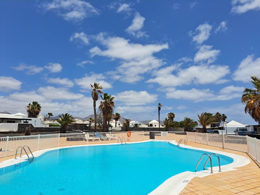 een groot zwembad met blauw water en palmbomen bij Bella Blanca in Playa Blanca