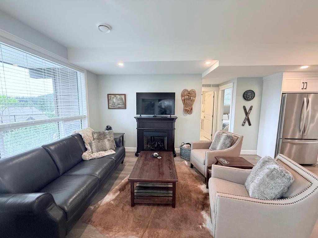 a living room with a leather couch and a fireplace at Peaks & Waters at Harrison Mills in Agassiz