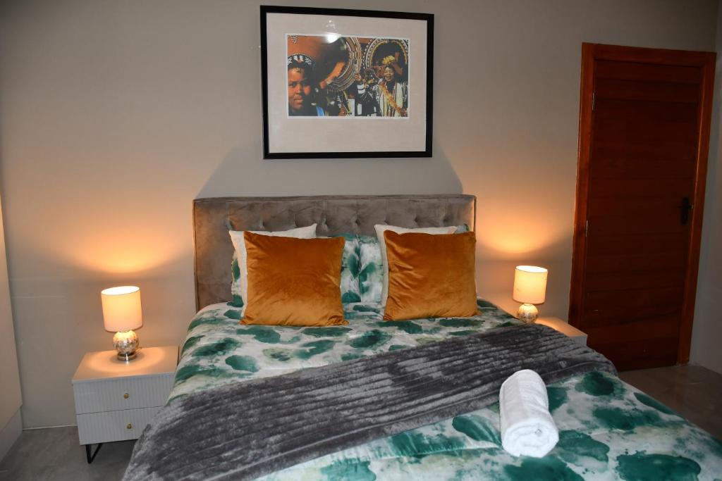 a bedroom with a bed with orange pillows and two lamps at Setlhoa one bed apartment in Gaborone
