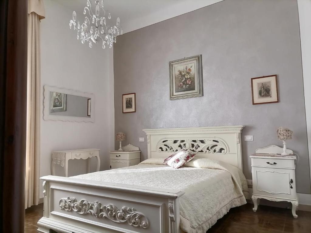 a bedroom with a white bed and a chandelier at Affittacamere Genia in Pisa