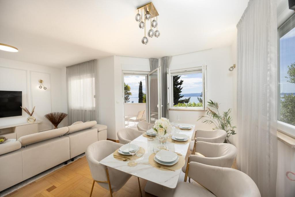 een witte woonkamer met een tafel en stoelen bij Marivi - Luxury apartment above the beach Žnjan in Split