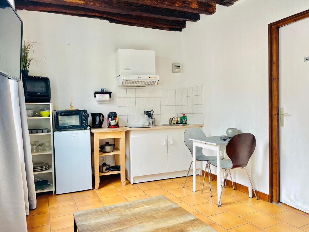 une petite cuisine avec une table et un réfrigérateur dans l'établissement Le Refuge de Bourgogne, à Orléans