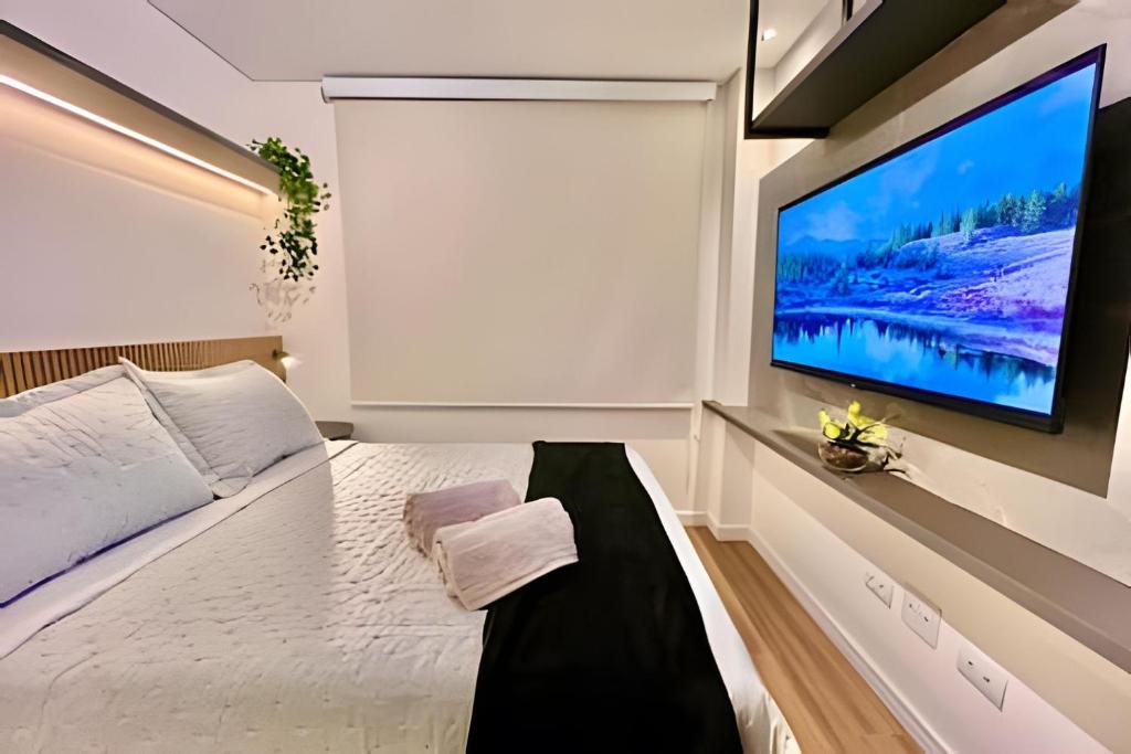 een slaapkamer met een grote flatscreen-tv aan de muur bij Memoravel, Com Estilo e com gosto in Curitiba