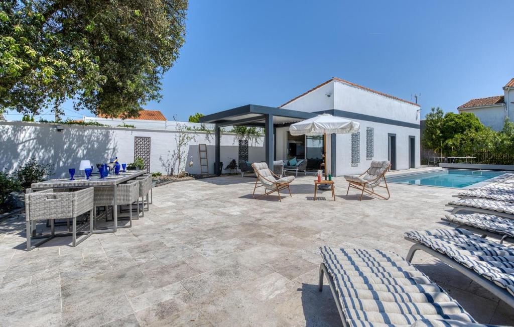 eine Terrasse mit Tisch und Stühlen und einem Pool in der Unterkunft Stunning Home In Royan in Royan