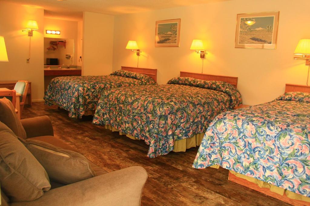a hotel room with three beds and a couch at Sunrise Motor Inn in Cody