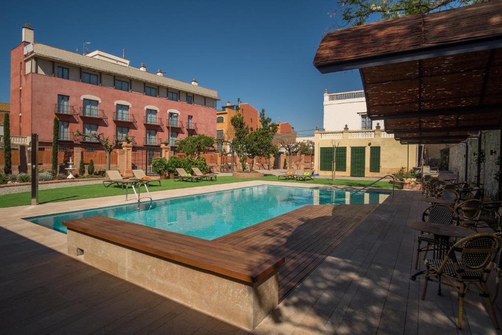 una piscina con un banco de madera junto a un edificio en Apartaments Suites Sant Jordi, en Montbrió del Camp