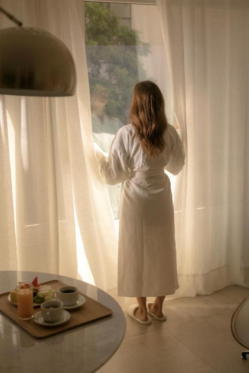 a woman in a white dress looking out of a window at Hub Hotel Asuncion in Asuncion