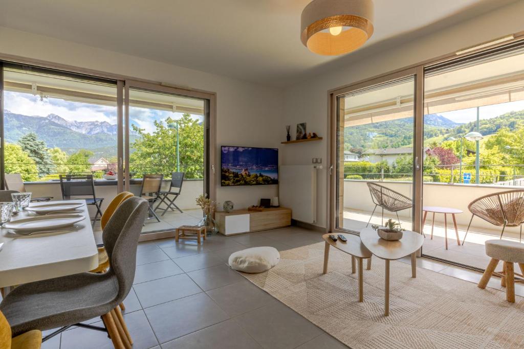 een woonkamer met een tafel en stoelen en grote ramen bij Tournette, vue montagne & belle terrasse in Annecy