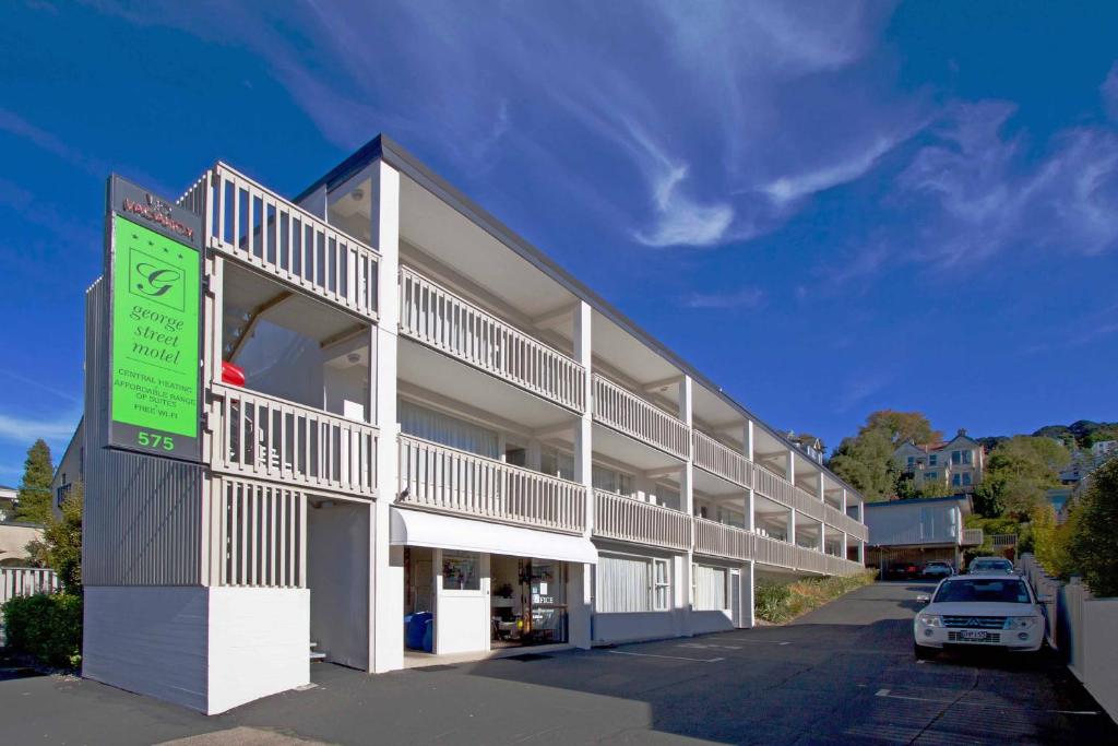 een gebouw waar een auto voor geparkeerd staat bij George Street Motel Apartments in Dunedin