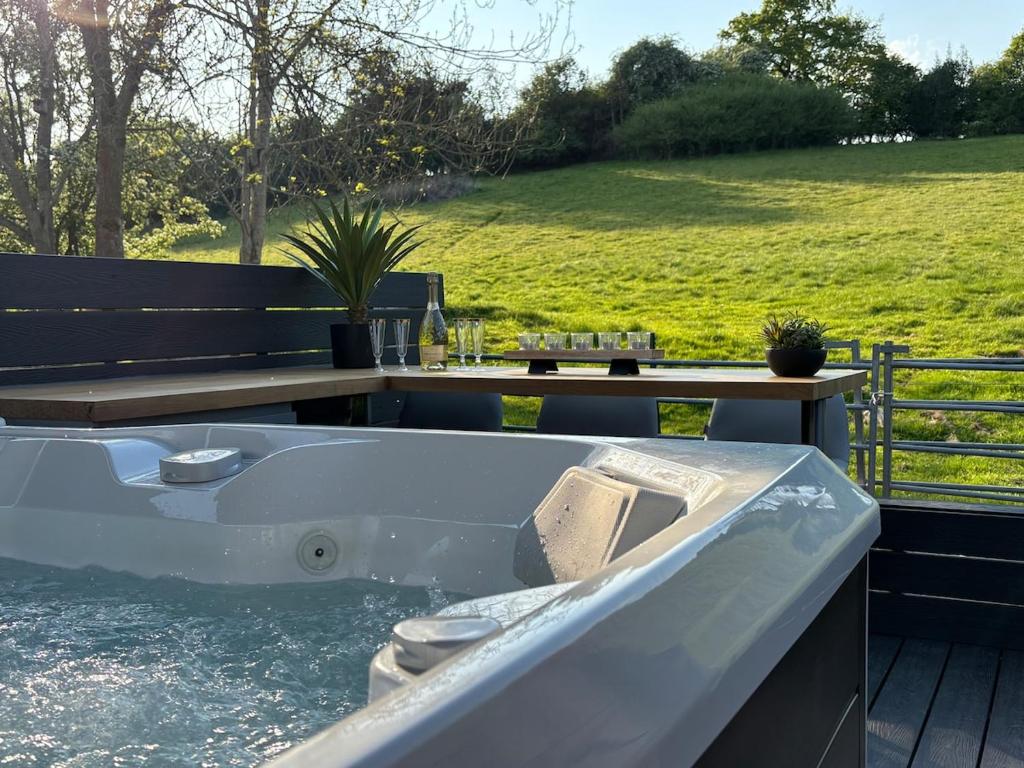 un bain à remous sur une terrasse avec une table et un terrain dans l'établissement Hill View Cottage, à Mappleton