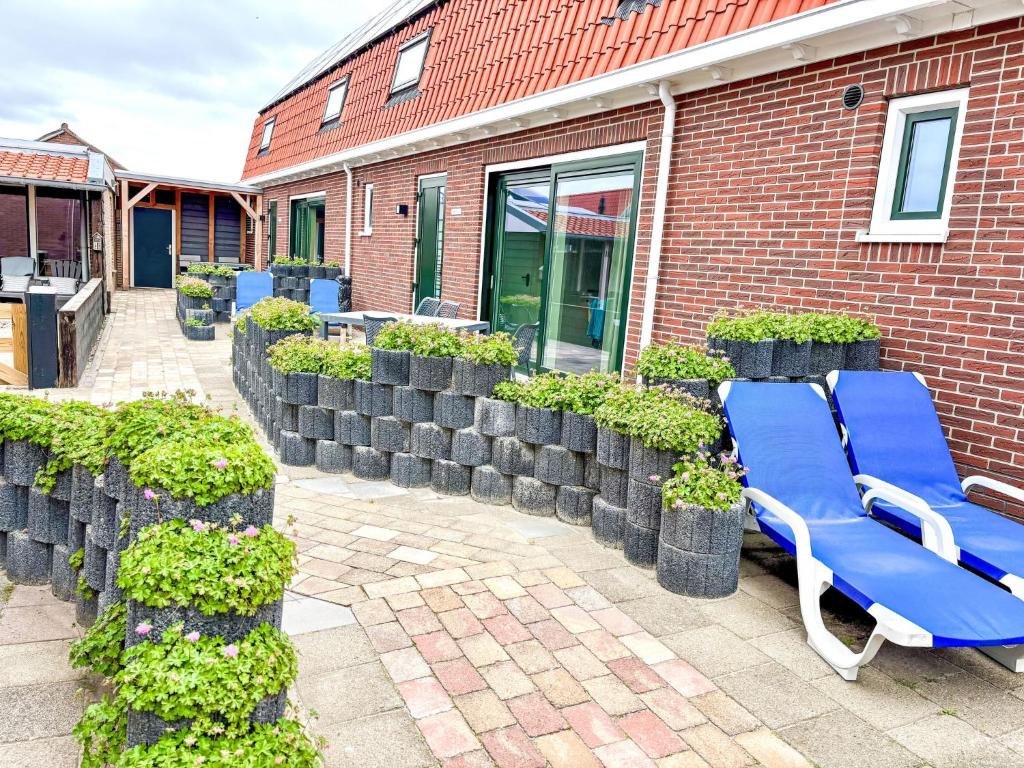 Un banco azul en un patio al lado de un edificio de ladrillo. en Holiday Home Beach House Westkapelle 103 D by Interhome, en Westkapelle