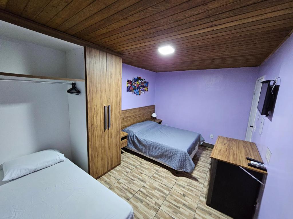 a small room with two beds and a desk at Alice Suites in Arraial do Cabo