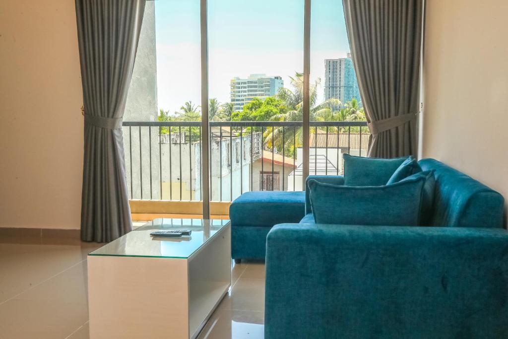 a living room with a blue couch and a large window at The Loft at Elixia in Sri Jayewardenepura Kotte