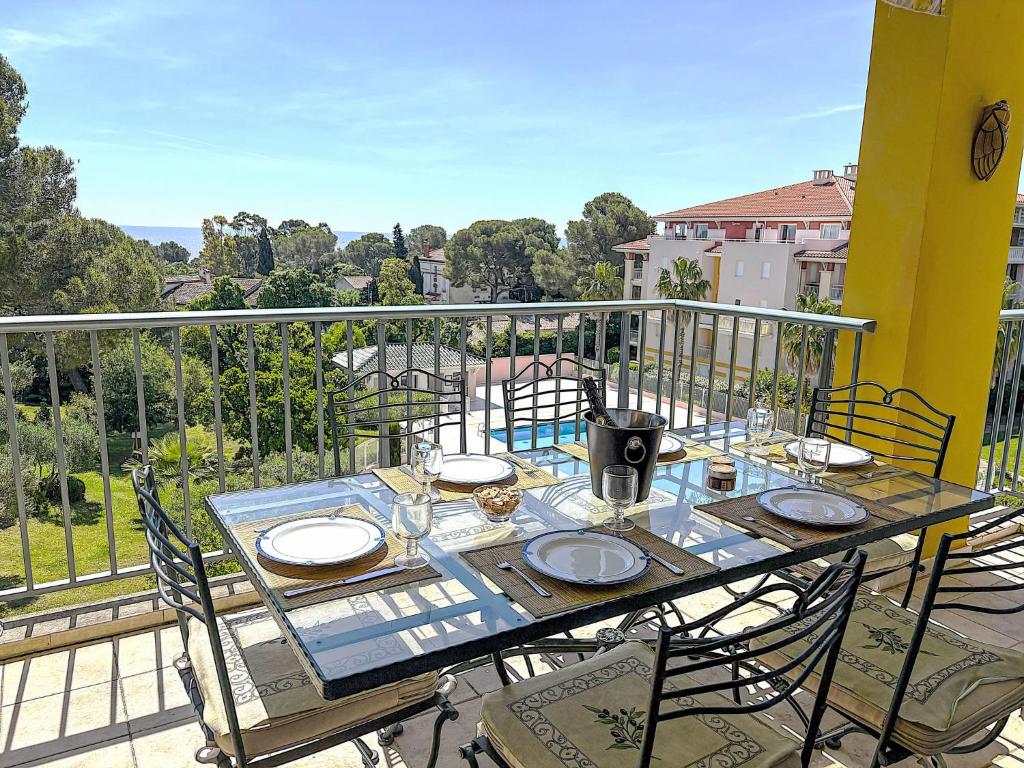 une table avec des assiettes et des verres sur un balcon dans l'établissement Apartment Le Grand Parc-11 by Interhome, à Saint-Aygulf