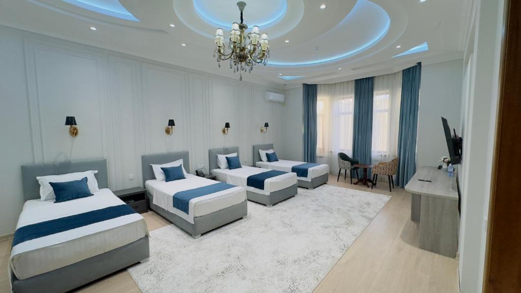 Un dormitorio con dos camas y un escritorio y una lámpara de araña. en Turon City Hotel, en Samarkand