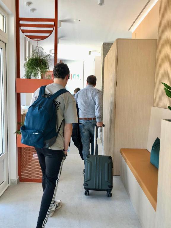 two men walking down a hallway with their luggage at Moebius - Habitaciones privadas con baño in León